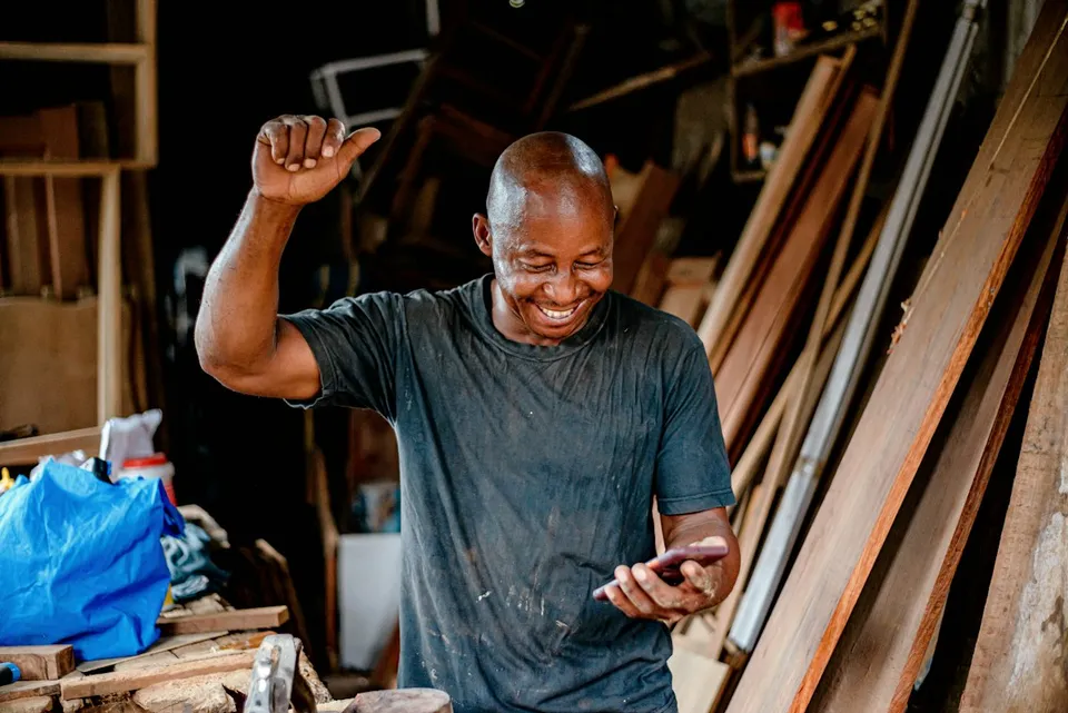 Un menuisier sourit en lisant un message dans son atelier