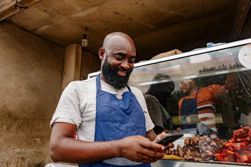 Un grilleur regarde son téléphone devant ses brochettes